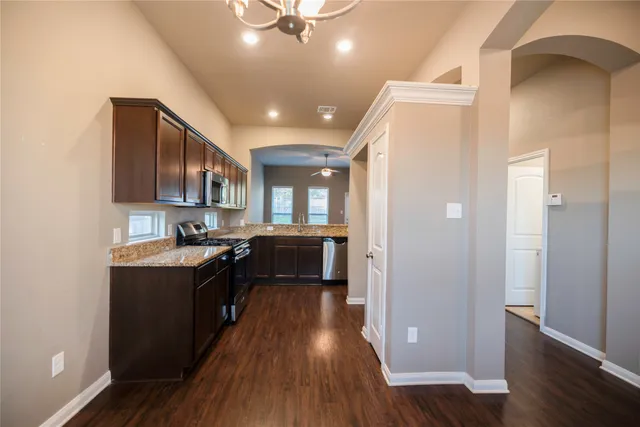 a kitchen with kitchen island granite countertop a sink cabinets and wooden floor