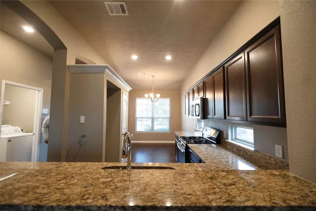 a view of a kitchen with kitchen island granite countertop a sink refrigerator dining table and chairs