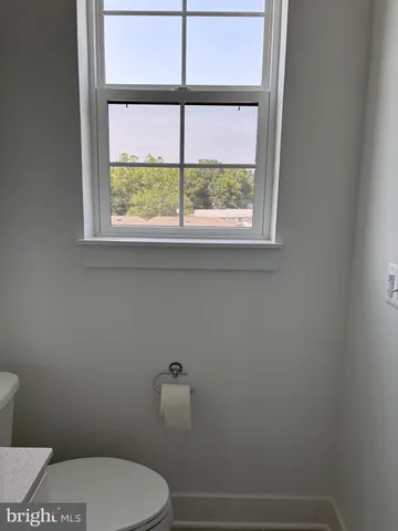 a white toilet sitting next to a window in a bathroom