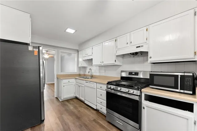 a kitchen with stainless steel appliances white cabinets and stove top oven