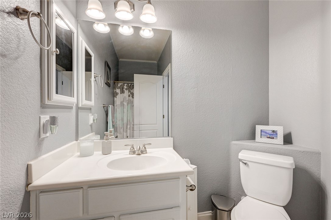 1604 Cattle Ranch Place Henderson, NV 89002 - Photo 60 of 99 A well-lit bathroom features a vanity with a white countertop, mirror, and toilet.