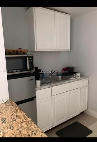 a kitchen with white cabinets and sink