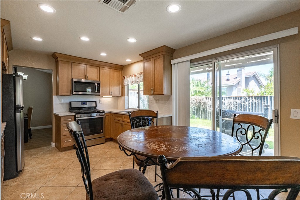 651 Viewpointe Lane Corona, CA 92881 - Photo 9 of 28 a kitchen with a dining table chairs and refrigerator