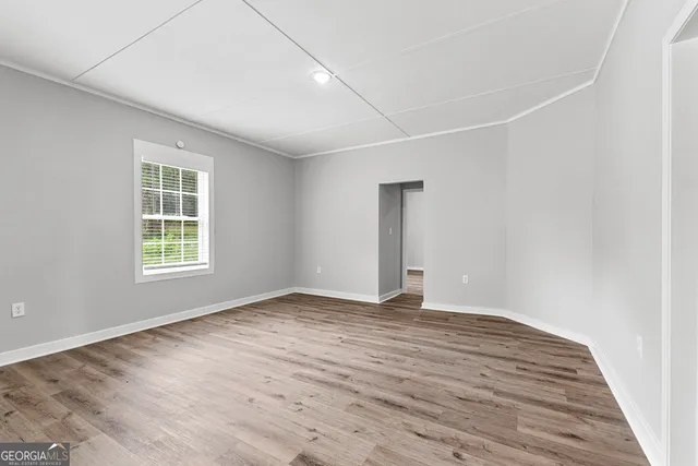a view of an empty room with wooden floor and a window