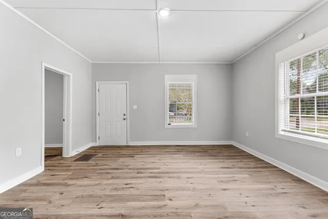 an empty room with wooden floor and windows