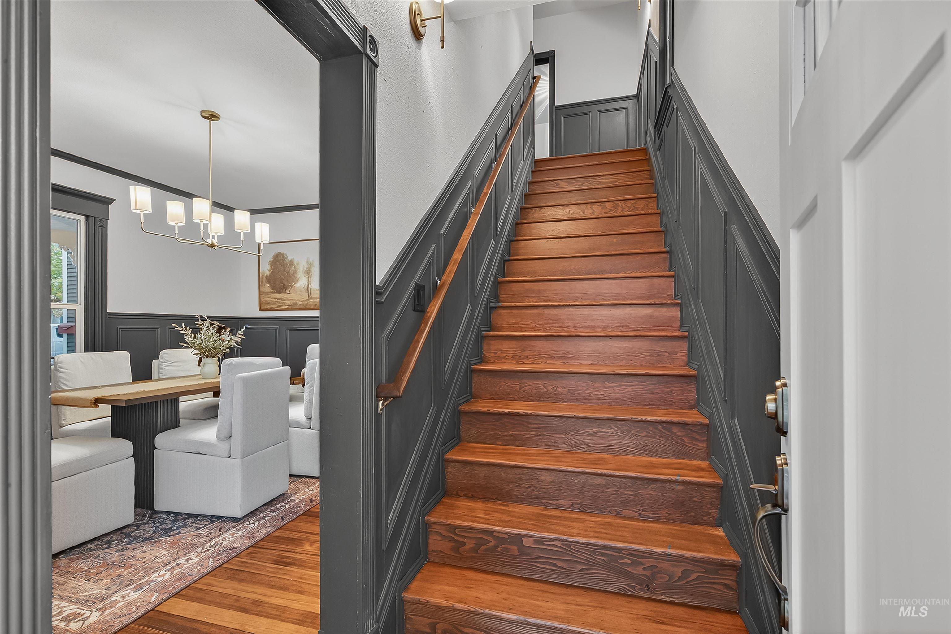 302 7th Avenue Lewiston, ID 83501 - Photo 21 of 50 Stairway featuring a decorative wall, a wainscoted wall, wood finished floors, and a chandelier