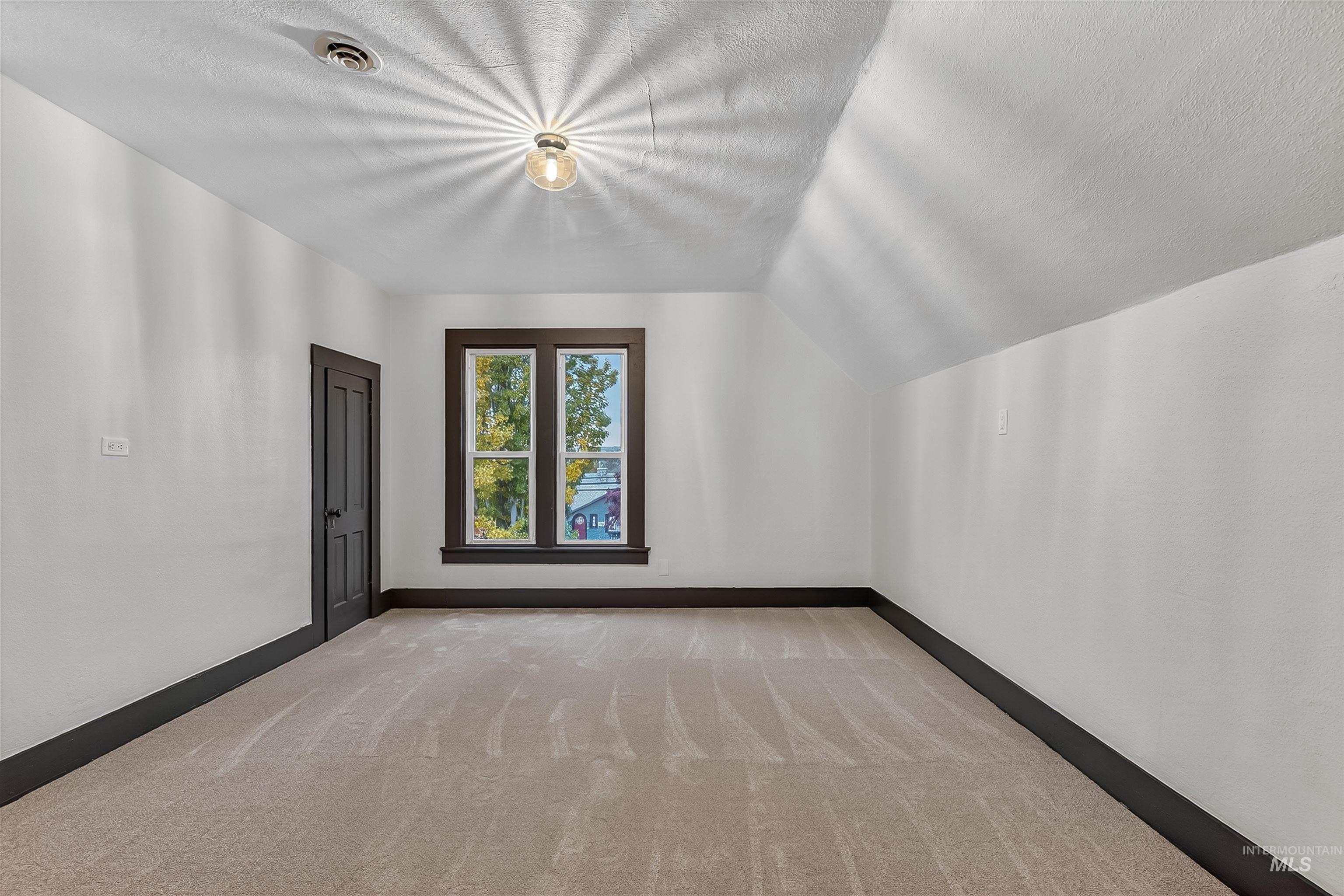 302 7th Avenue Lewiston, ID 83501 - Photo 23 of 50 Additional living space with carpet flooring, a textured ceiling, and lofted ceiling