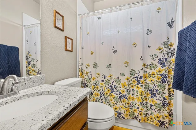 a bathroom with a granite countertop sink and a toilet
