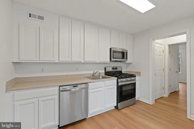 a kitchen with white cabinets and stainless steel appliances