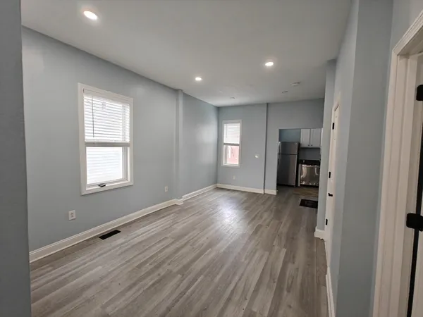 a view of empty room with wooden floor and window