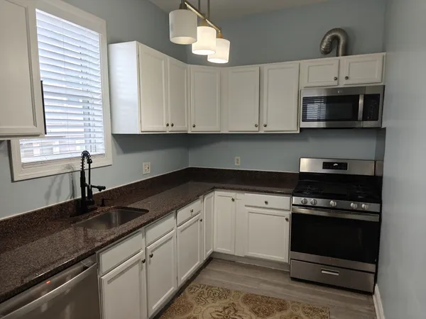 a kitchen with granite countertop white cabinets and a stove