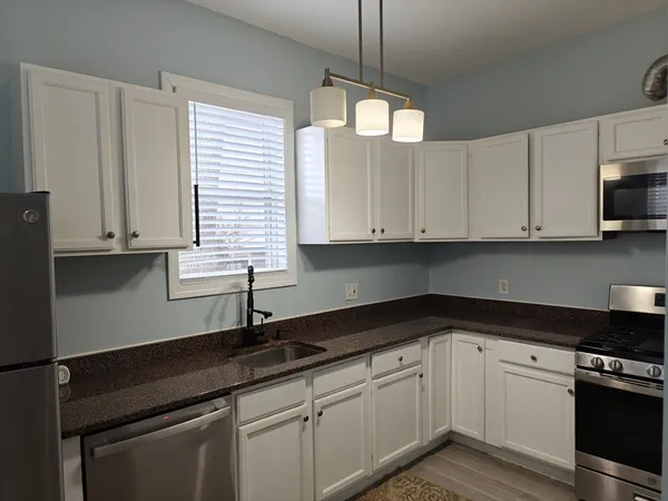 a kitchen with stainless steel appliances granite countertop white cabinets and a sink