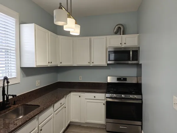 a kitchen with white cabinets and a stove top oven