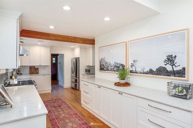 a living room with stainless steel appliances furniture a rug and a large window