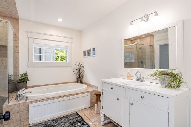 a bathroom with a granite countertop sink vanity mirror bathtub and toilet