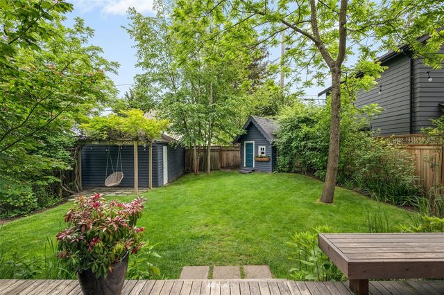 a view of a backyard with table and chairs potted plants and large tree