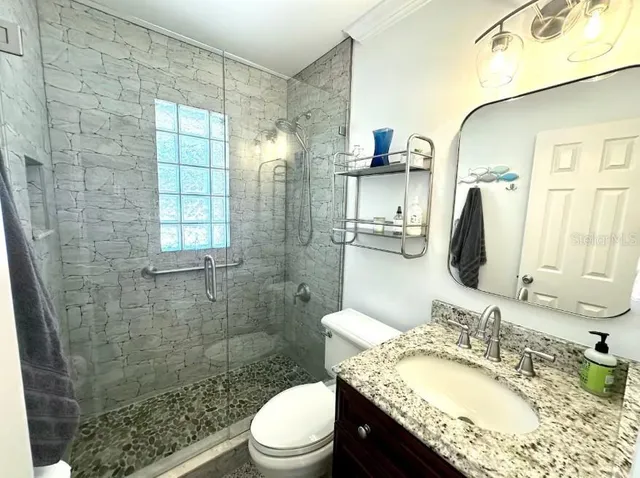 a bathroom with a granite countertop sink toilet and shower