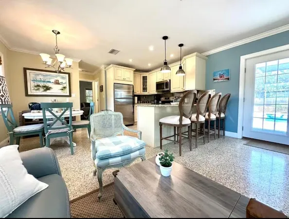 a living room with furniture kitchen view and a wooden floor