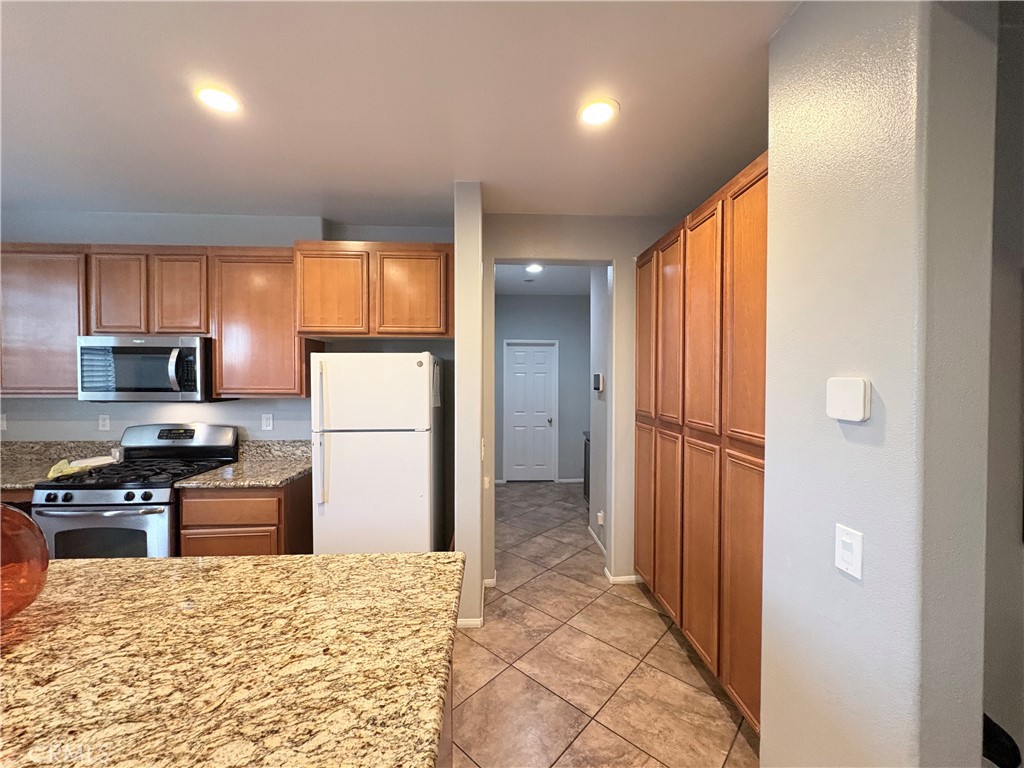 2729 Hornbeam Road Palmdale, CA 93551 - Photo 11 of 35 a kitchen with stainless steel appliances granite countertop a refrigerator and a stove top oven