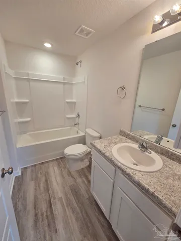 a bathroom with a granite countertop sink a toilet and shower