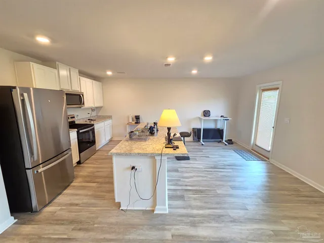 a kitchen view with stainless steel appliances wooden floor and living room view