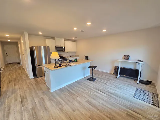 a living room with stainless steel appliances kitchen island granite countertop furniture a refrigerator and wooden floor