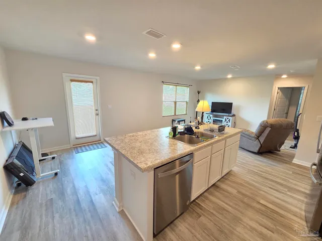 a kitchen with a sink appliances and wooden floor