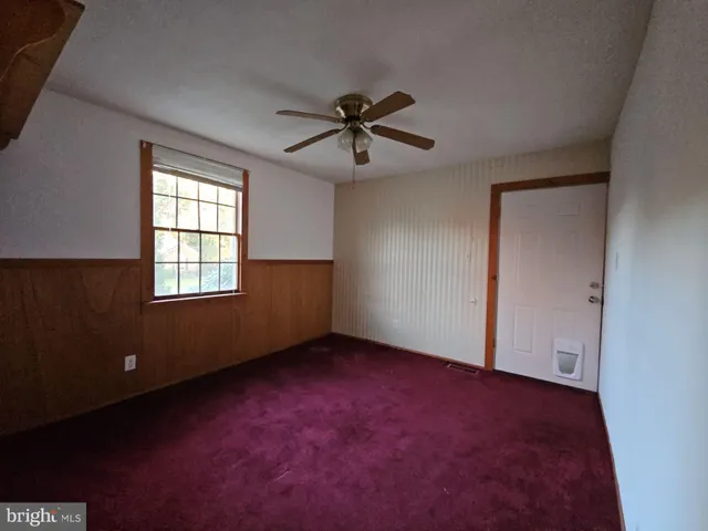 an empty room with windows and fan
