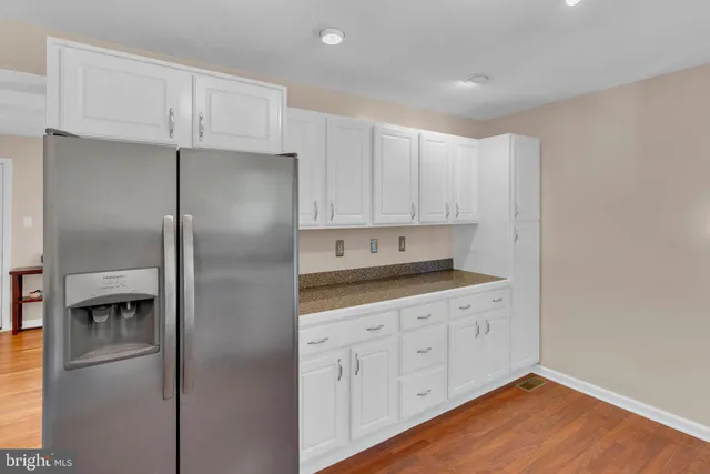 a kitchen with white cabinets and refrigerator