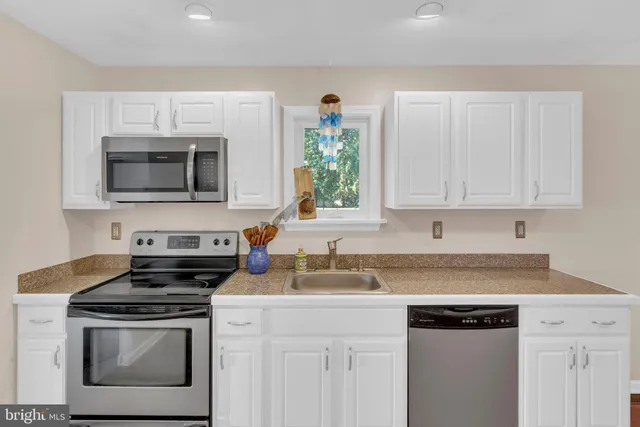 a kitchen with granite countertop a stove a sink and a microwave