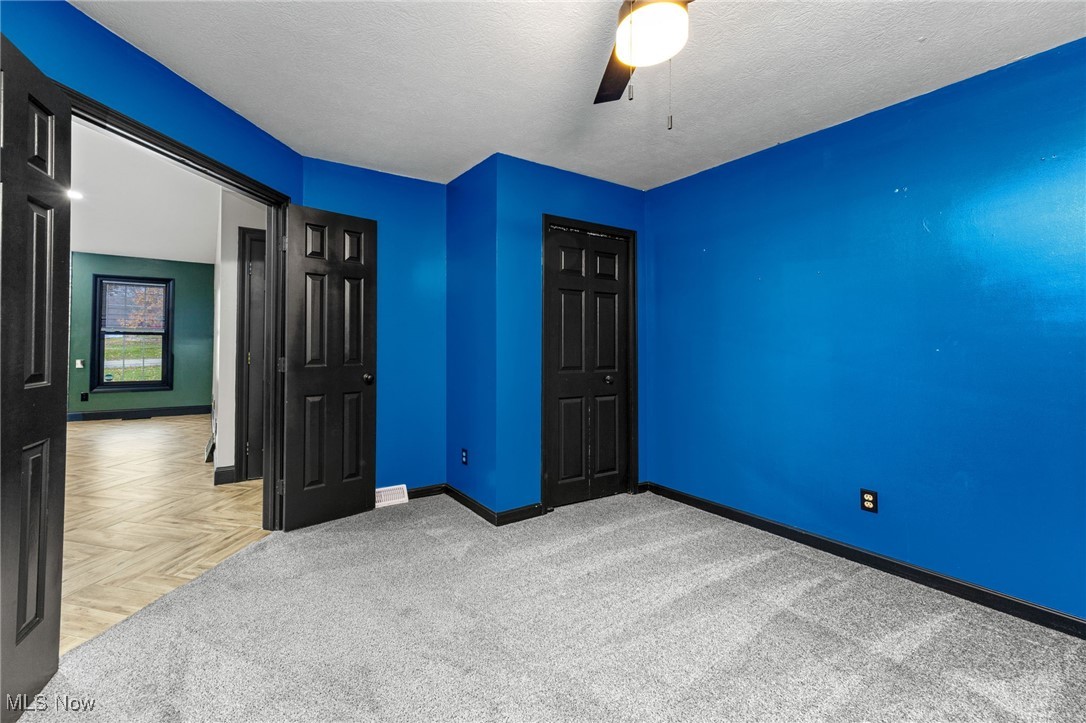 2840 Wadsworth Road Barberton, OH 44203 - Photo 18 of 32 Unfurnished bedroom with ceiling fan, a textured ceiling, a closet, and carpet