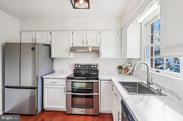 a kitchen with a refrigerator sink and white cabinets