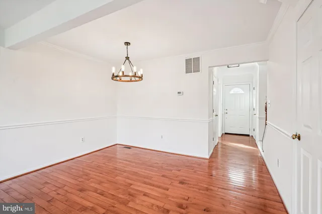 an empty room with wooden floor and chandelier