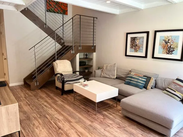 a living room with couches and a dining table with wooden floor