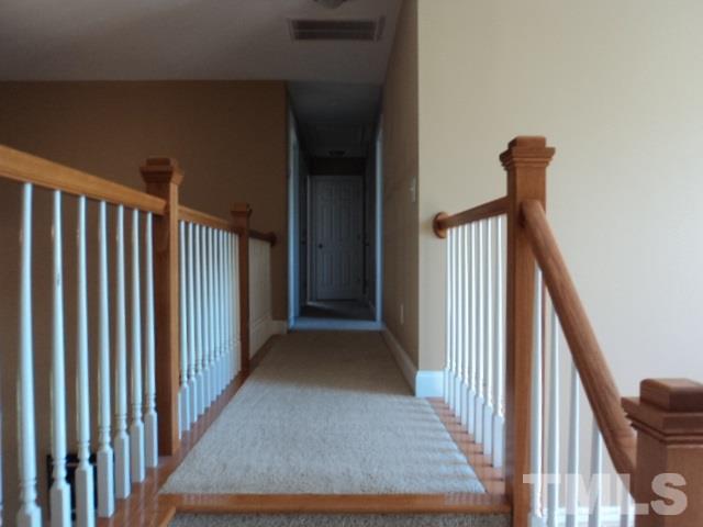 1108 Coram Fields Road Wake Forest, NC 27587 - Photo 13 of 24 a view of a hallway with wooden floor and stairs