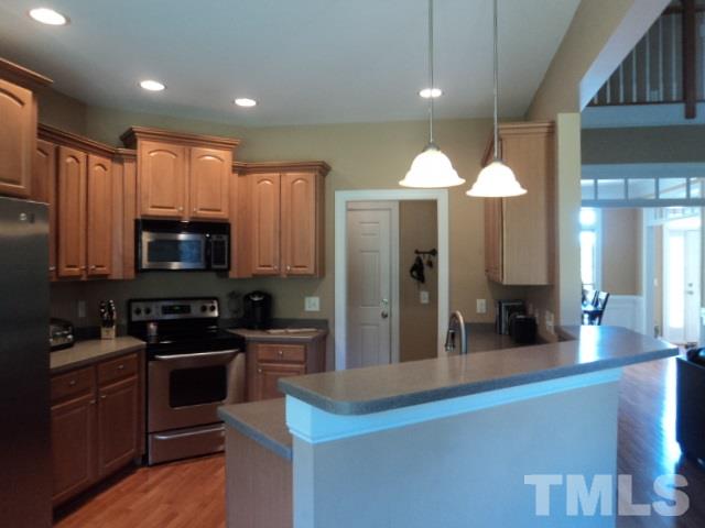 1108 Coram Fields Road Wake Forest, NC 27587 - Photo 6 of 24 a kitchen with kitchen island granite countertop wooden cabinets and a sink
