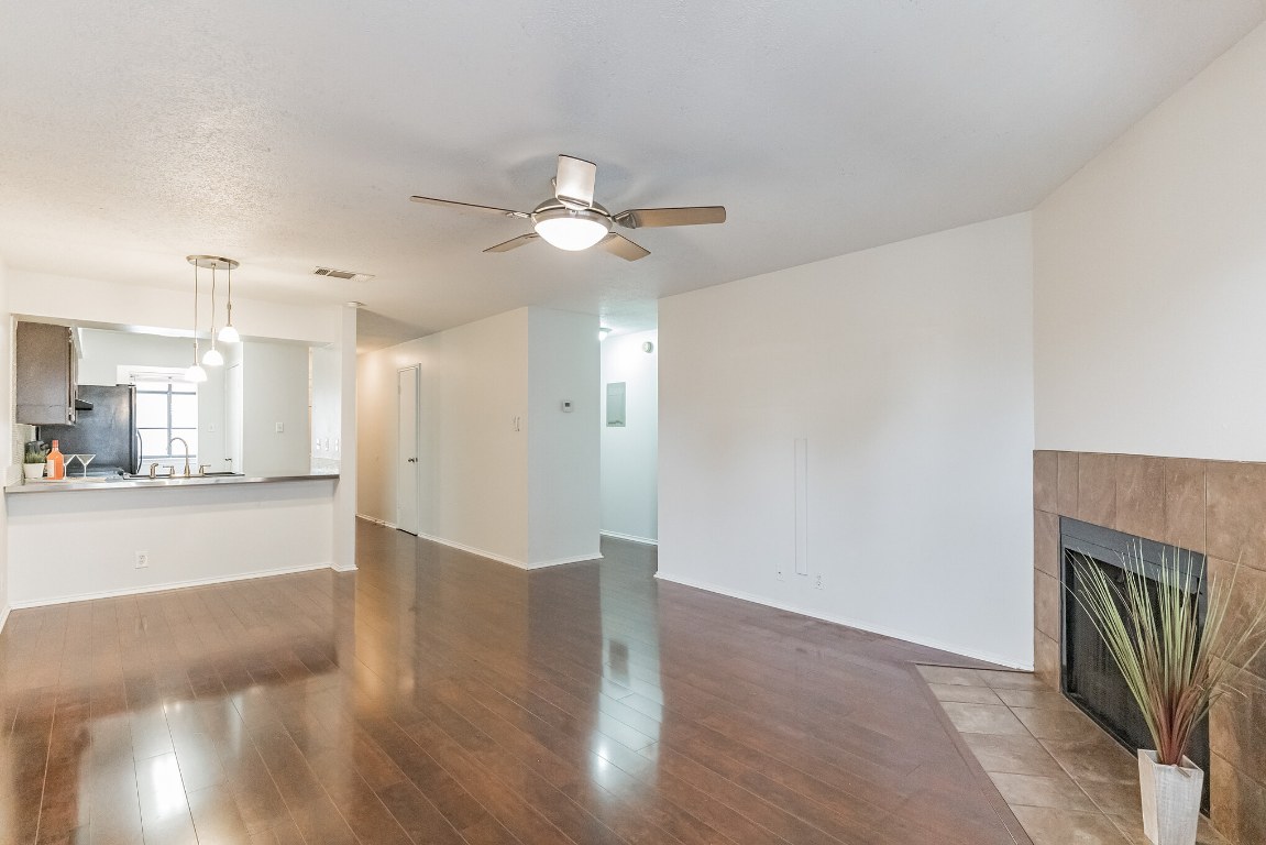a view of a livingroom with a fireplace a ceiling fan and wooden floor
