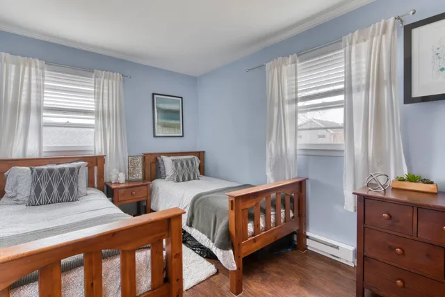 a bedroom with two beds and next to a window