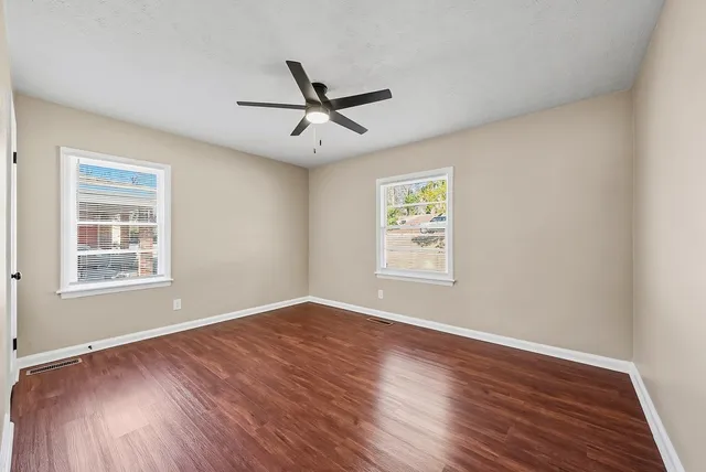 a view of empty room with wooden floor and fan