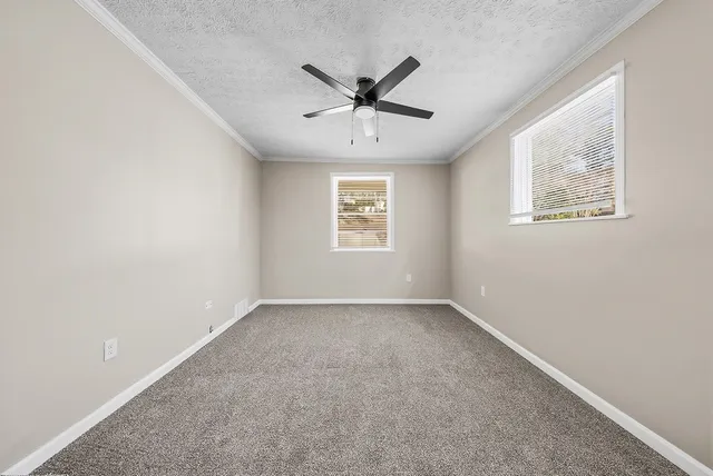 an empty room with windows and fan