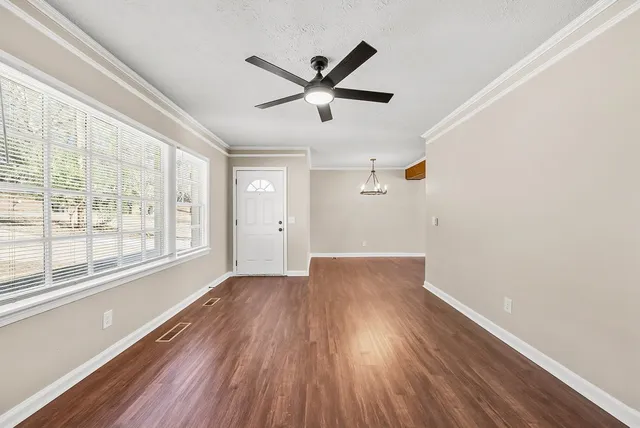 a view of empty room with wooden floor and fan