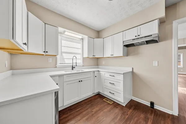 a kitchen with cabinets appliances wooden floor and a window