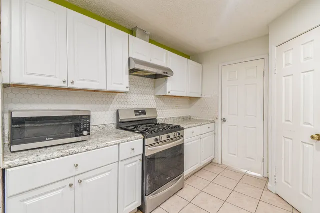 a kitchen with stainless steel appliances granite countertop a refrigerator and a stove