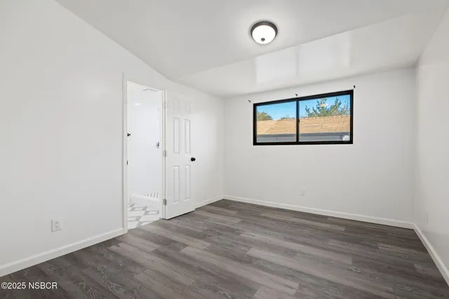 an empty room with wooden floor and window