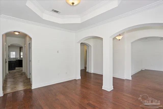 an empty room with wooden floor chandelier fan and windows