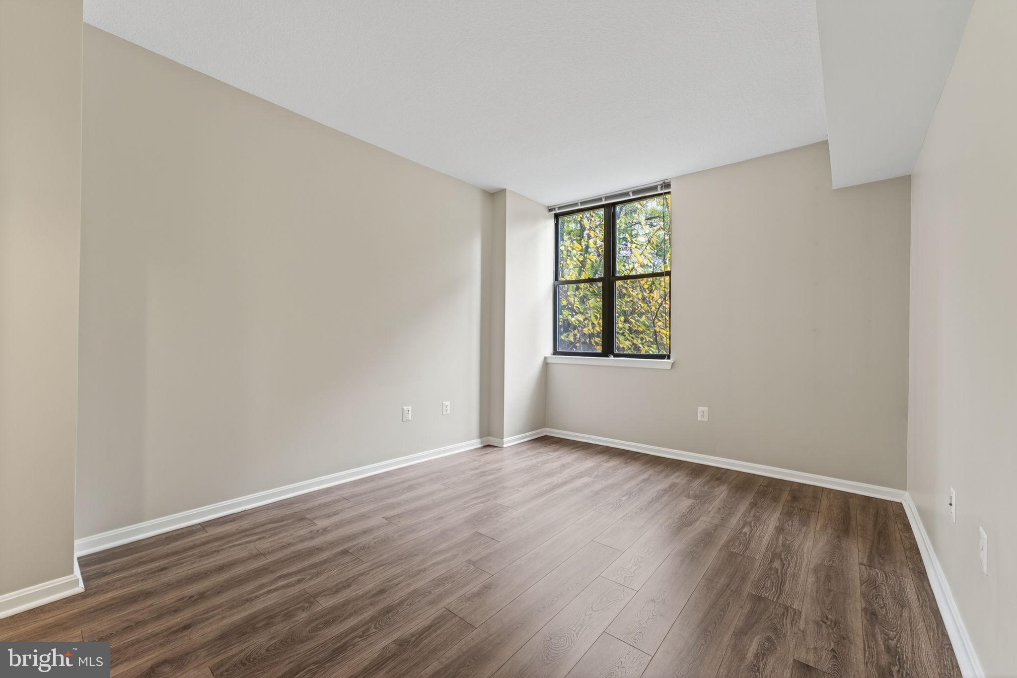 2220 Fairfax Drive, Unit 206 Arlington, VA 22201 - Photo 16 of 25 a view of an empty room with wooden floor and a window