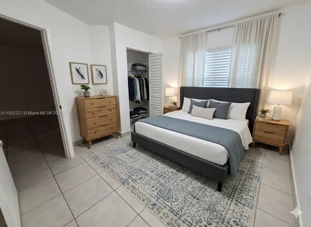 a bedroom with a bed and a flat tv screen on dresser