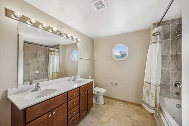 a bathroom with a double vanity sink toilet and shower