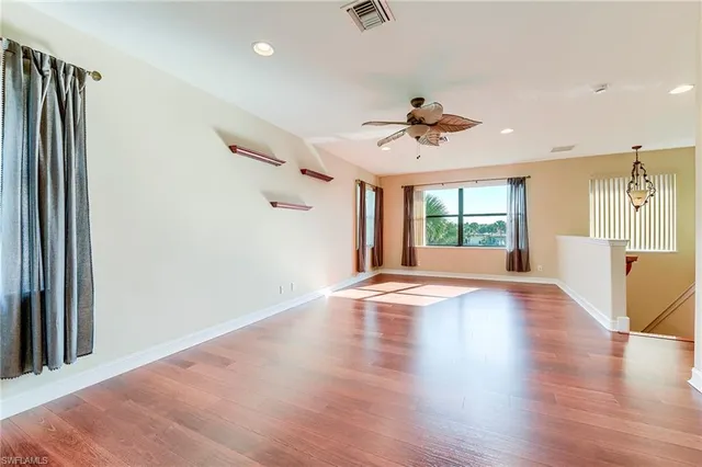 an empty room with wooden floor and chandelier fan