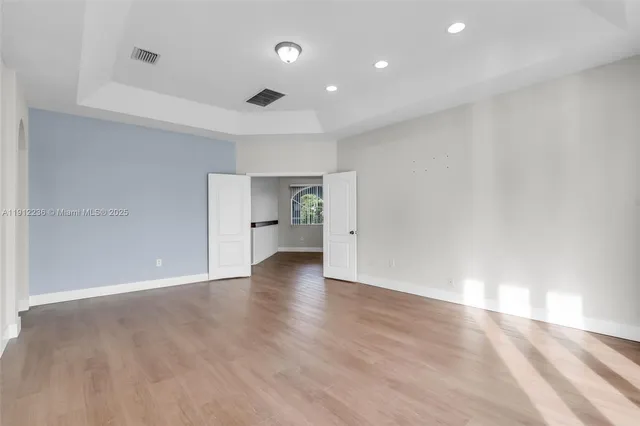 a view of an empty room with wooden floor and window